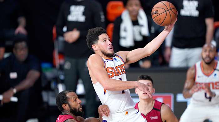 Aug 8, 2020; Lake Buena Vista, Florida, USA; Phoenix Suns' Devin Booker (1) goes to the basket over Miami Heat's Andre Iguodala, left, and Tyler Herro, right, during the second half of an NBA basketball game at Visa Athletic Center.